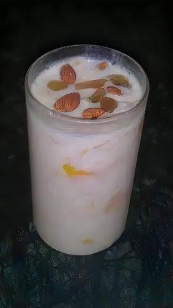 Creamy beverage topped with almond slices and saffron strands in a glassの写真素材