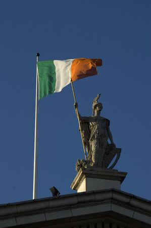 Statue and Irish Flag on top of the GPO in Dublin City shot from below with plenty of bright blue skyの写真素材