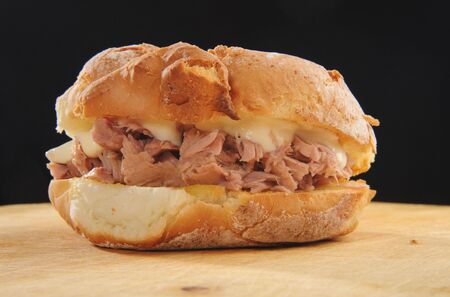 Tuna and Mayo in bread roll on a wooden table, shot against black.の写真素材