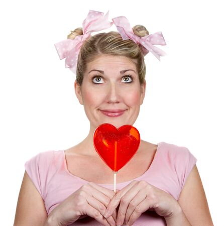 a silly or humorous woman holding a valentines heart, dressed as a child with a silly look on her face.の写真素材