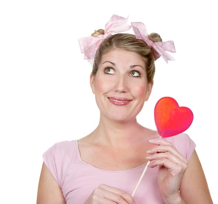 a funny or silly woman looking up smiling holding a valentines heart, wearing pink, isolated on a white backgroundの写真素材