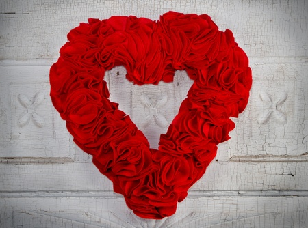 a handmade felt heart hangs on a vintage or antique door, the antique door is the backgroundの写真素材
