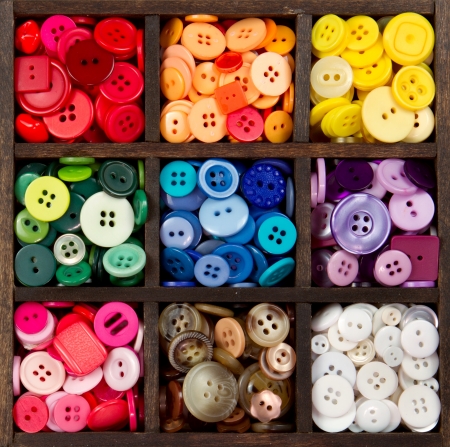 an assortment of buttons in a rainbow of colors, in a printers boxの写真素材