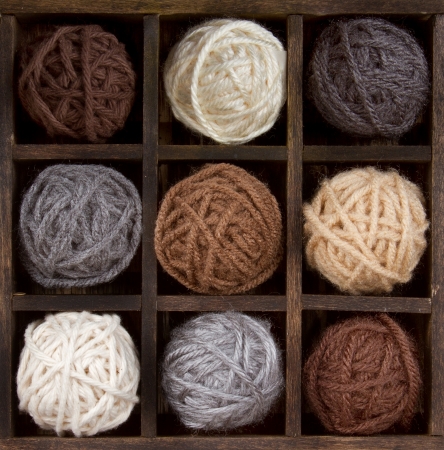 Assorted balls of natural colored yarn in a printers boxの写真素材