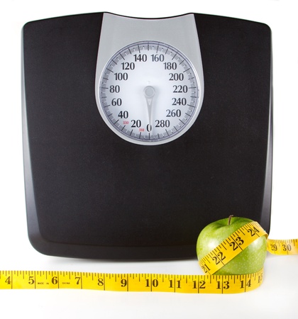 An apple with a measuring tape around it with a scale in the background, white background. Room for copy-space on the scale.の写真素材