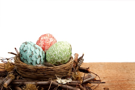 paper covered easter eggs in a nest on a white background room for copy spaceの写真素材