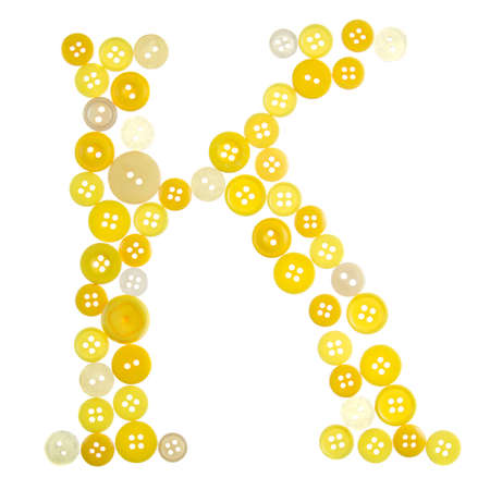 The letter K made of photographed buttons, isolated on a white backgroundの写真素材