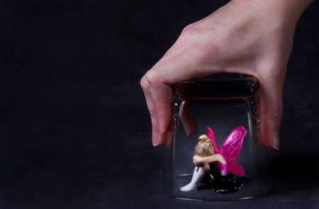 A young fairy trapped under a glass, looking sad, room for copyspaceの写真素材