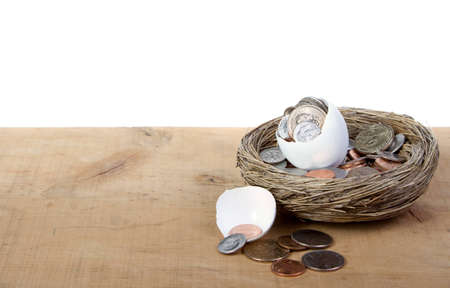 A cracked open egg with coins spilling out, a business conceptの写真素材