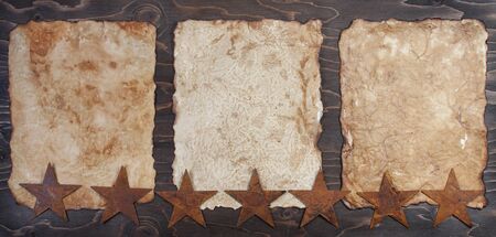 Three vintage papers on a wooden background with rusty starsの写真素材