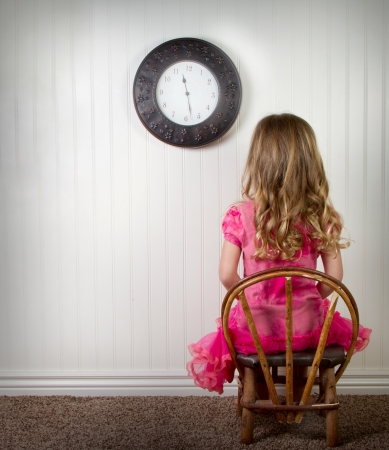 A young child in time out or in trouble, with clock on wallの写真素材