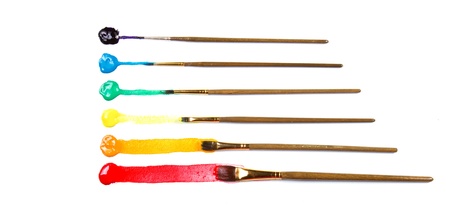 Assorted paint brushes on canvas background with lines of paint on white background