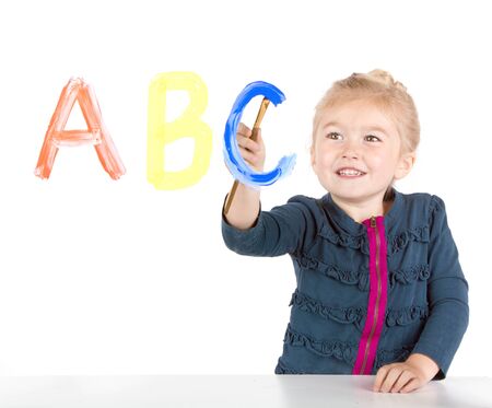 Little girl paints ABC's or letters on windowの写真素材