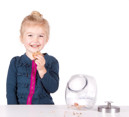 Girl stealing cookie out of cookie jar isolated on white backgroundの写真素材