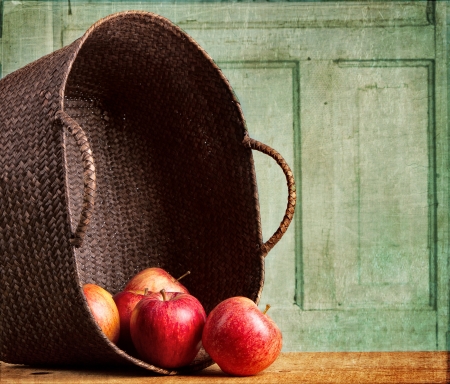 Apples spilling out of a basket on grunge background, vintage or antique lookの写真素材