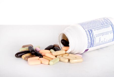 Vitamins spilling out of a bottle, assorted varieties isolated backgroundの写真素材