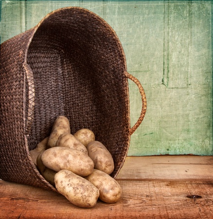 Russet potoatoes spilling out of a basket on wooden crate, grunge backgroundの写真素材
