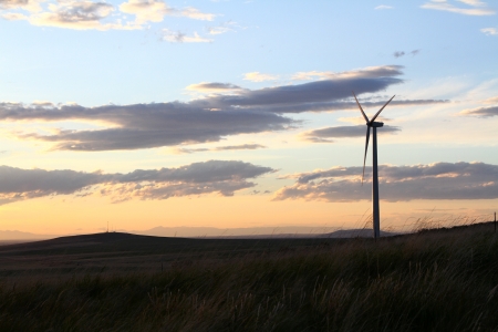 A windmill on a hillside sillouetted by a sunsetの写真素材