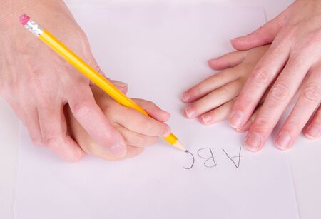  Close-up of mother or teacher helping young child to write alphabetの写真素材