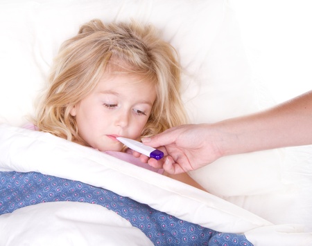 sick child with a thermometer in mouth lying in bedの写真素材