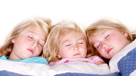 Three sisters sleeping or snuggling in bedの写真素材