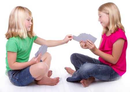 sisters or friends playing cards, white backgroundの写真素材