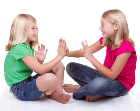 two girls playing clapping game, white backgroundの写真素材