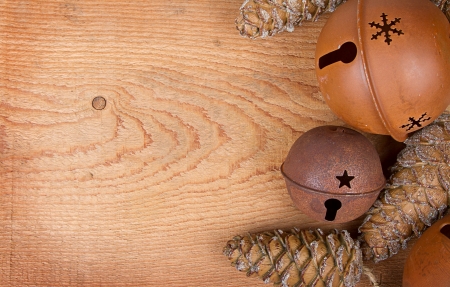 Chirstmas ornaments pinecones and rusty bells on a brown wood panelの写真素材