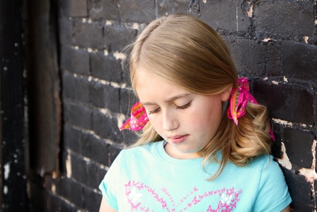 Close up of teen looking down by brick wall