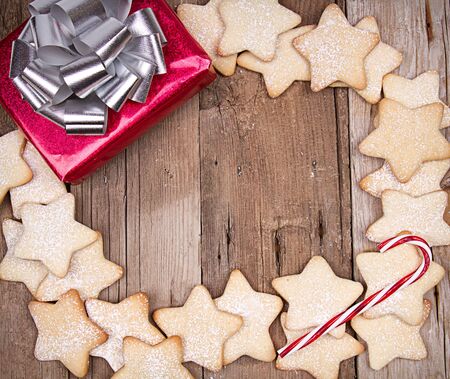 Christmas cookies framed on wooden background with present and candy caneの写真素材
