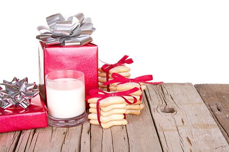 Christmas cookies and milk with presents on a wooden plankの写真素材
