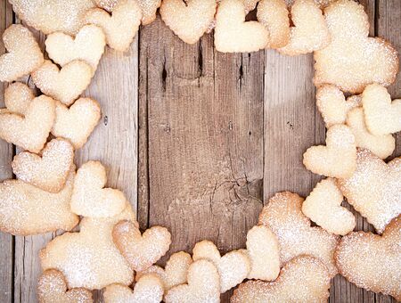 Heart shaped sugar cookies stacked framing a wooden backgroundの写真素材