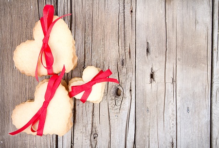 Heart shaped sugar cookie tied with red ribbon on wooden backgroundの写真素材