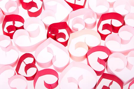 Paper shaped like a heart in shades of pink and red on a white backgroundの写真素材