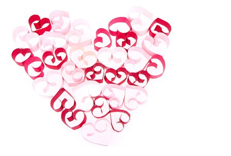 Paper shaped like a heart in shades of pink and red on a white backgroundの写真素材