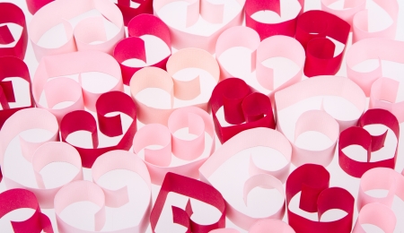 Paper shaped like a heart in shades of pink and red on a white backgroundの写真素材