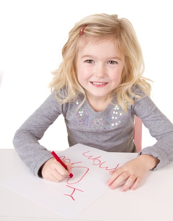Little girl writting I love you mom, on white paper, isolated on whiteの写真素材