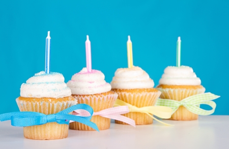 cupcakes with candles and bows on a blue background.の写真素材
