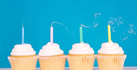 cupcakes with candles blown out and smoke on a blue backgroundの写真素材