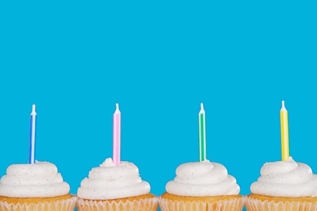 Vanilla cupcakes with candles with a blue background