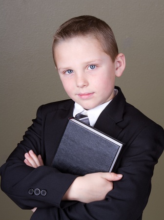 Boy holding book wearing a suitの写真素材