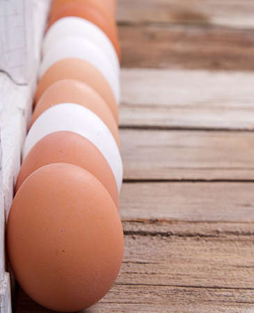 Brown and white eggs lined up  on a rustic wooden background