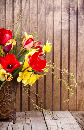 Spring flowers tulips and daffodils in a vase on a wooden backgroundの写真素材