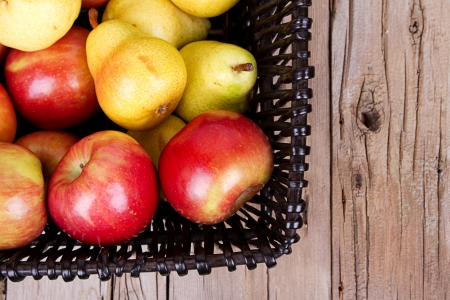 apples and pears in a basket on a wooden basketの写真素材