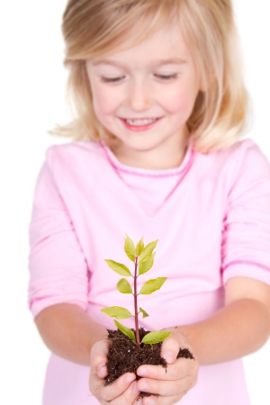 Young girl or child with a  plant while smiling, isolated on white の写真素材