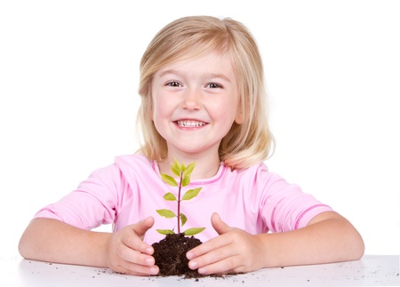 Young girl or child with a  plant while smiling, isolated on white の写真素材