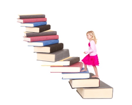 young child climbing a staircase of books with an isolated white backgroundの写真素材