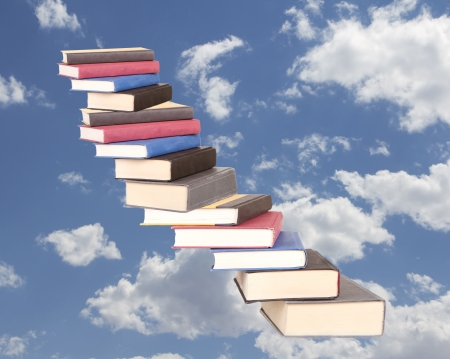 a stair case of books floating on a cloudy sky backgroundの写真素材