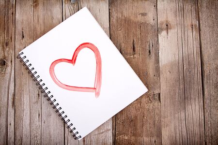 Painting of heart on notebook or sketch book with wooden planks for backgroundの写真素材