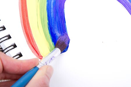 Painting of rainbow on notebook or sketch book with paintbrush, close-upの写真素材